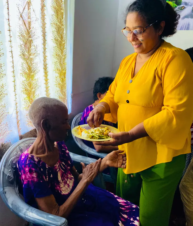 a woman serving food to a woman sitting in chairs